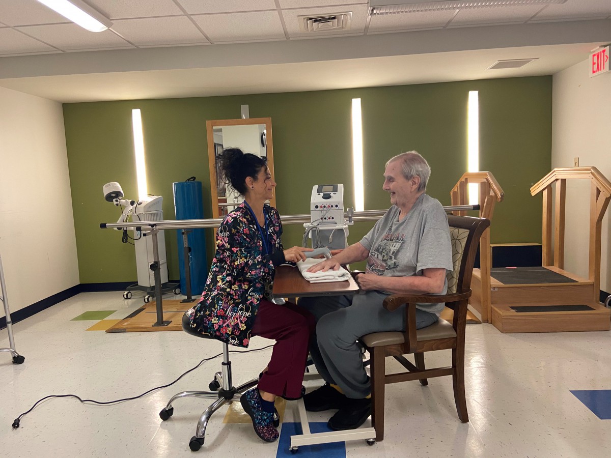 A therapist and an elderly patient engage in a rehabilitation session.
