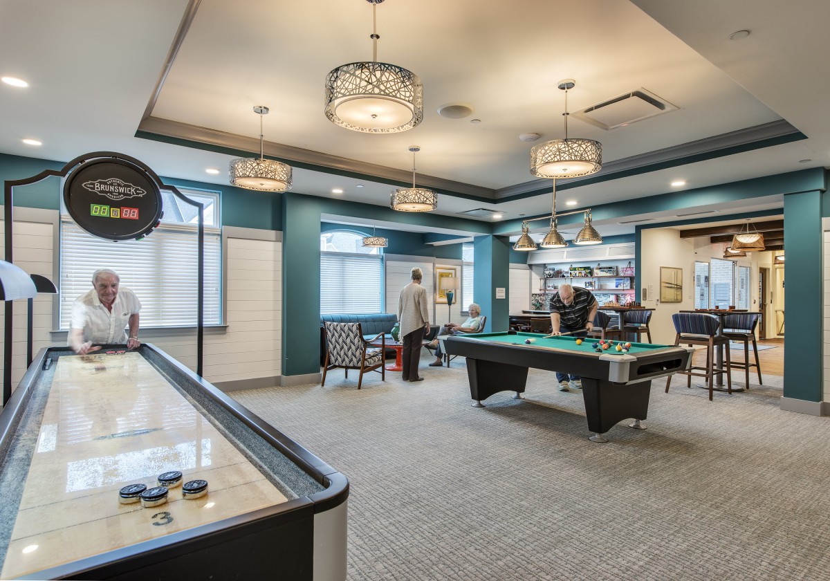 A modern game room featuring a pool table and shuffleboard with stylish lighting.