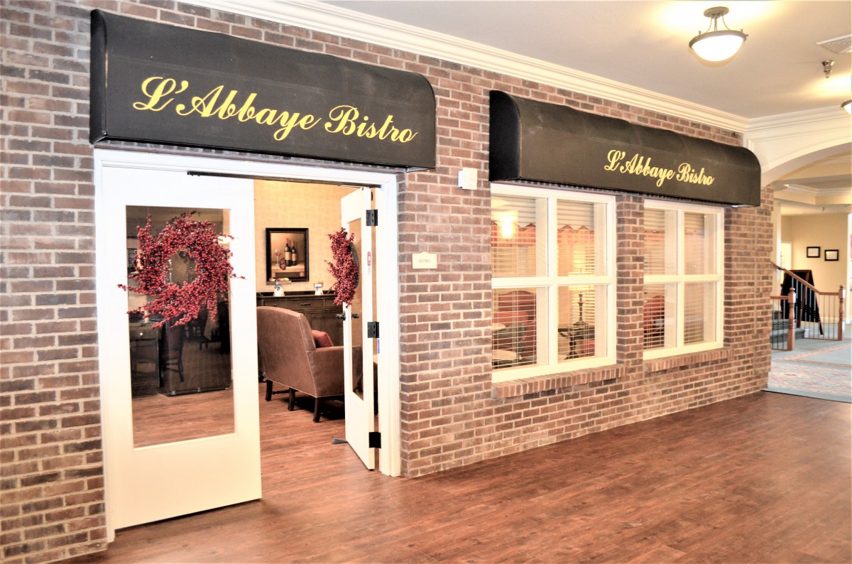 Entrance to L'Abbaye Bistro with brick walls and elegant signage.