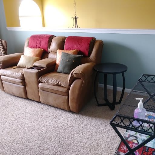 A cozy living room with a brown sofa, colorful cushions, and a side table.