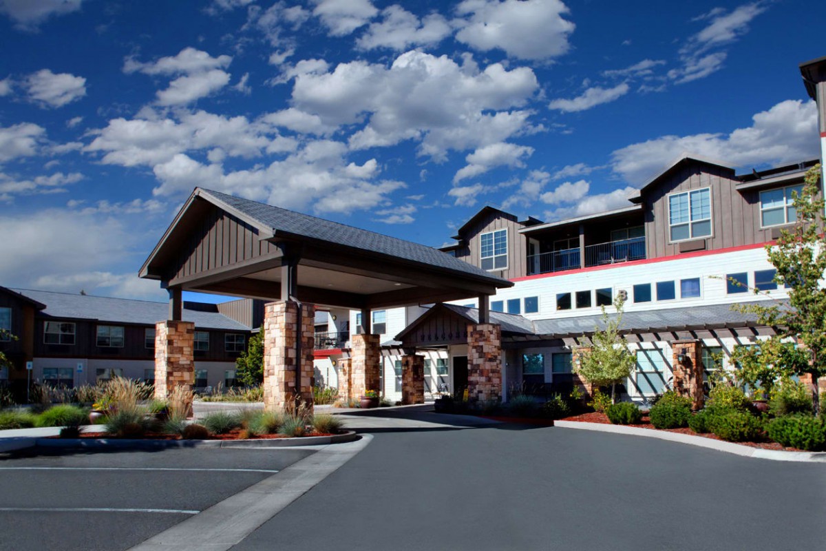 A modern hotel entrance with a covered driveway under a blue, cloudy sky.