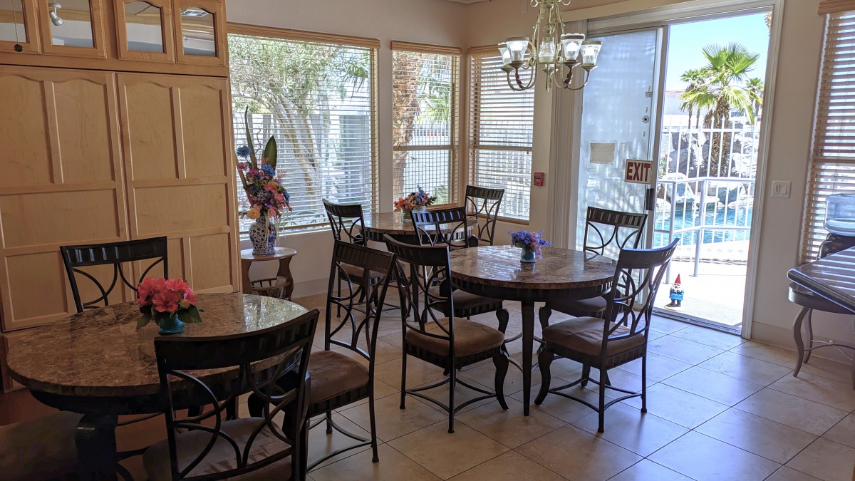 A cozy dining area with multiple tables and chairs, illuminated by natural light from large windows.