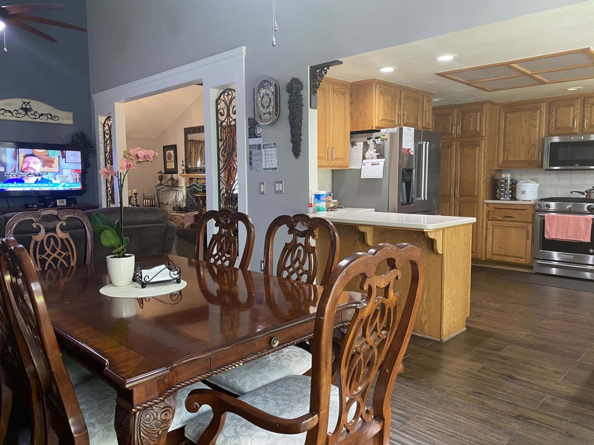 A spacious dining area with a wooden dining table and chairs, adjacent to an open-layout kitchen.