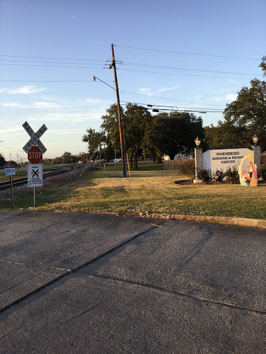A view of a railroad crossing with signage, set in an evening landscape.