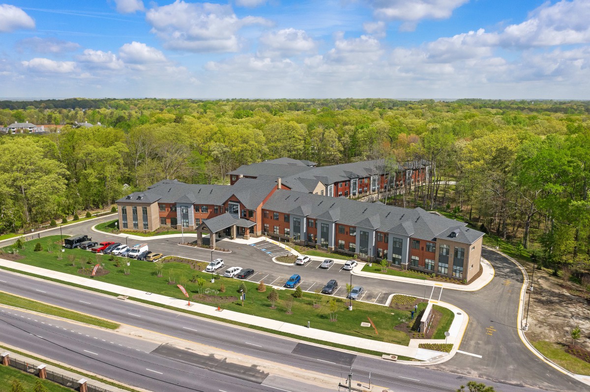 Aerial view of a modern building surrounded by greenery and roads.
