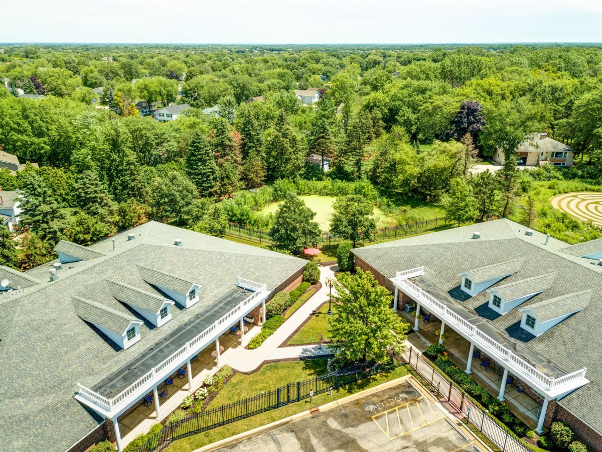 Aerial view of two buildings surrounded by lush greenery and trees.