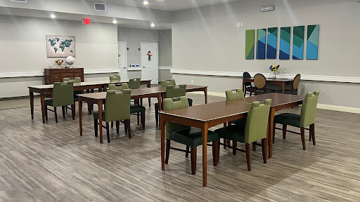 A spacious dining area featuring wooden tables and green chairs, designed with a modern aesthetic.