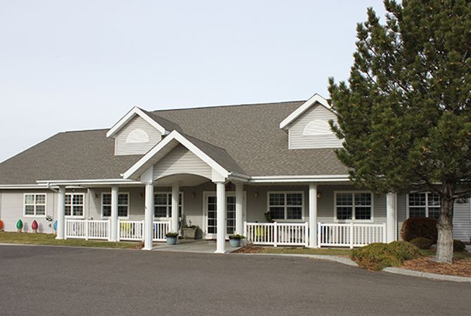 A residential building with a front porch and surrounding trees.