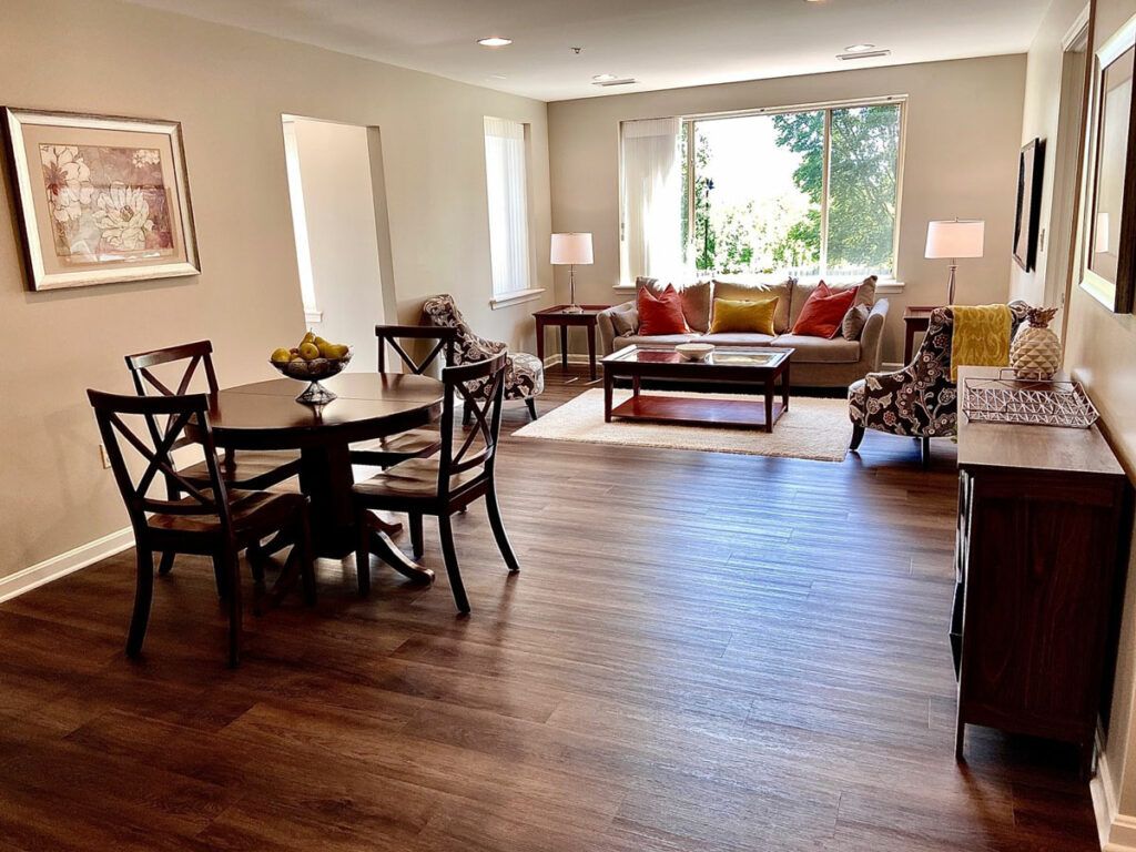 A spacious living room with a dining area, featuring wood flooring, comfortable seating, and ample natural light.