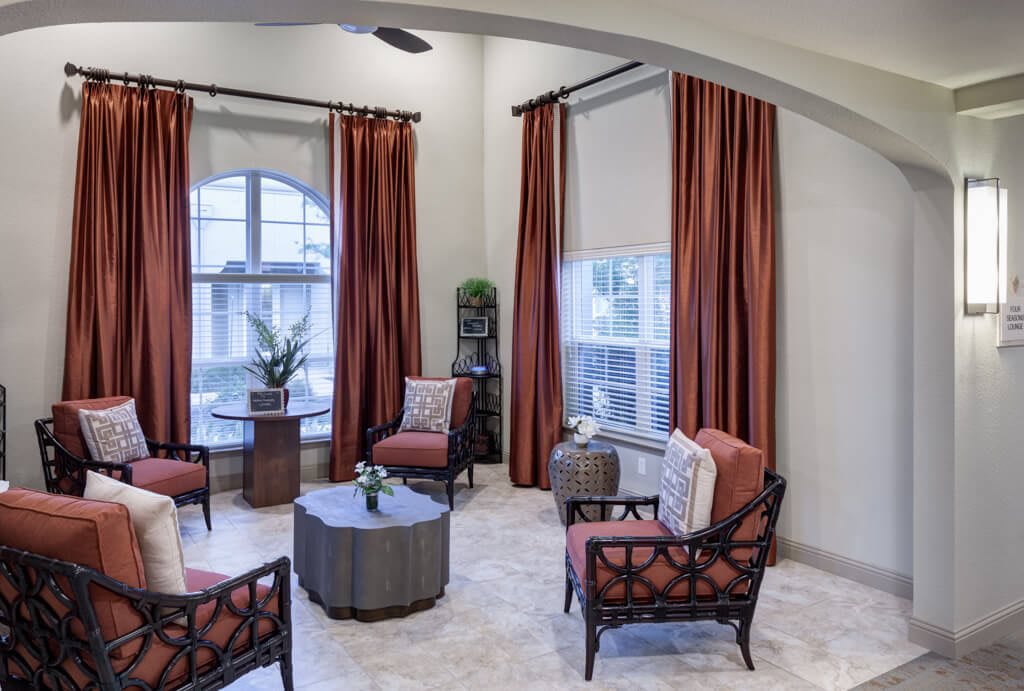 A modern living room with stylish seating and warm-toned curtains.