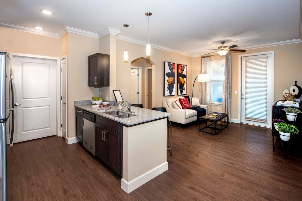 A modern open-concept kitchen and living room with hardwood floors and contemporary furniture.