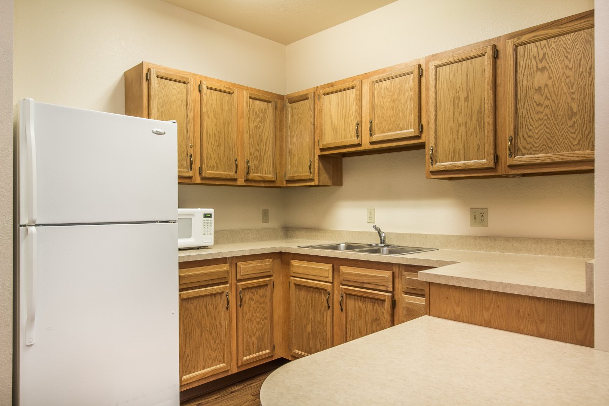 A simple kitchen with wooden cabinets and basic appliances.