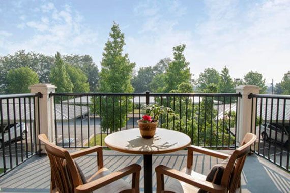 A peaceful balcony with a small table and chairs overlooking a lush, green landscape.