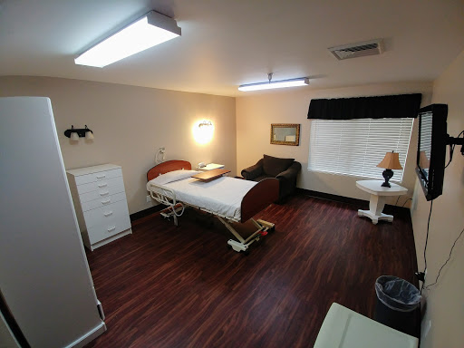 A well-furnished hospital room featuring a medical bed, seating area, and ambient lighting.