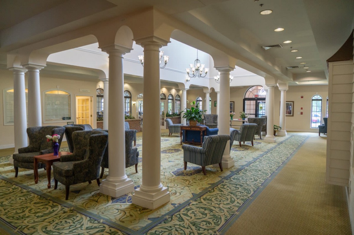 A spacious, elegantly decorated lounge area featuring comfortable seating, ornate columns, and chandeliers.