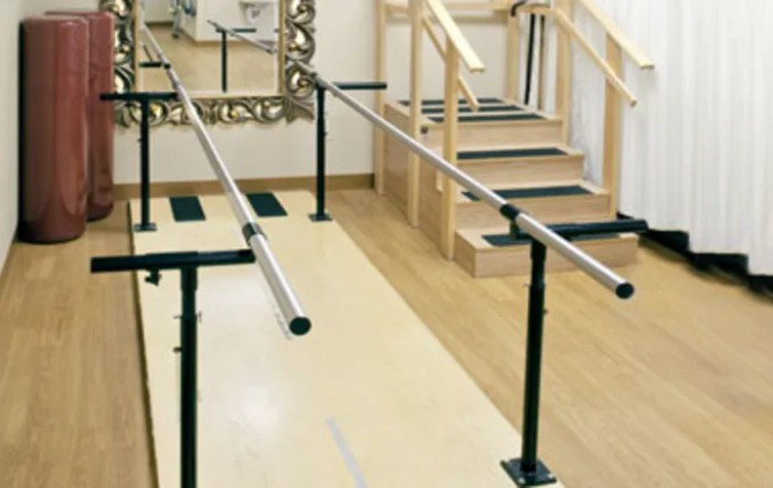 A rehabilitation room equipped with parallel bars and stairs for physical therapy exercises.