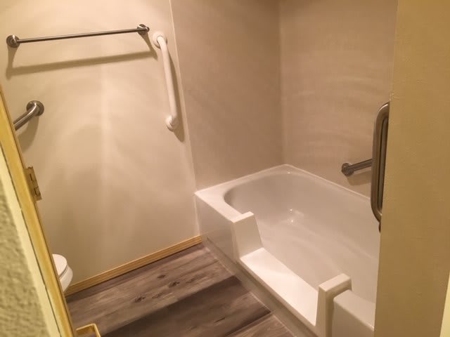 A minimalist bathroom with a bathtub and towel rack.