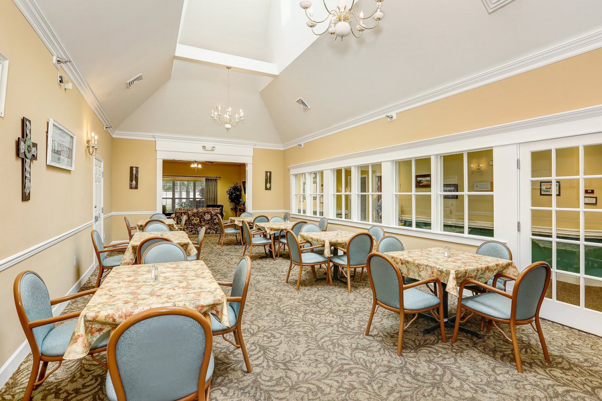 A well-lit dining room with multiple tables and chairs, set in a spacious interior.