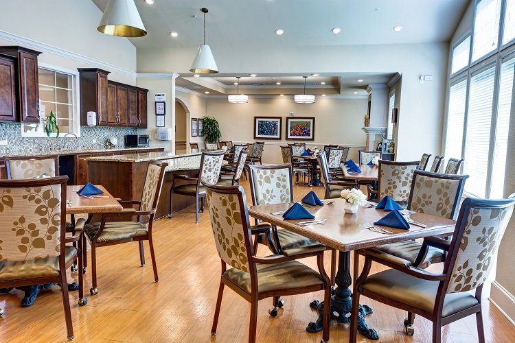 A well-furnished dining room with neatly arranged tables and chairs, featuring elegant lighting and decor.