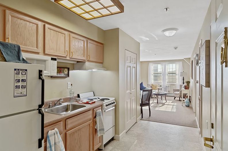 A cozy apartment featuring a compact kitchen area with wooden cabinets and adjacent living room space.