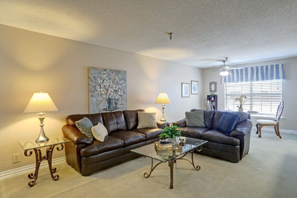 A cozy living room featuring two large sofas, a glass coffee table, and warm lighting.