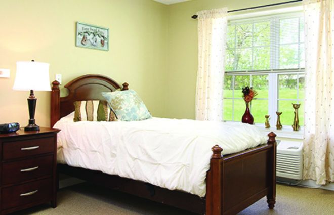 A cozy bedroom with a single bed and a large window adorned with light curtains.