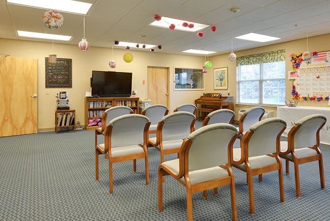 A classroom or conference room setup with rows of chairs facing a television, decorated with hanging ornaments.