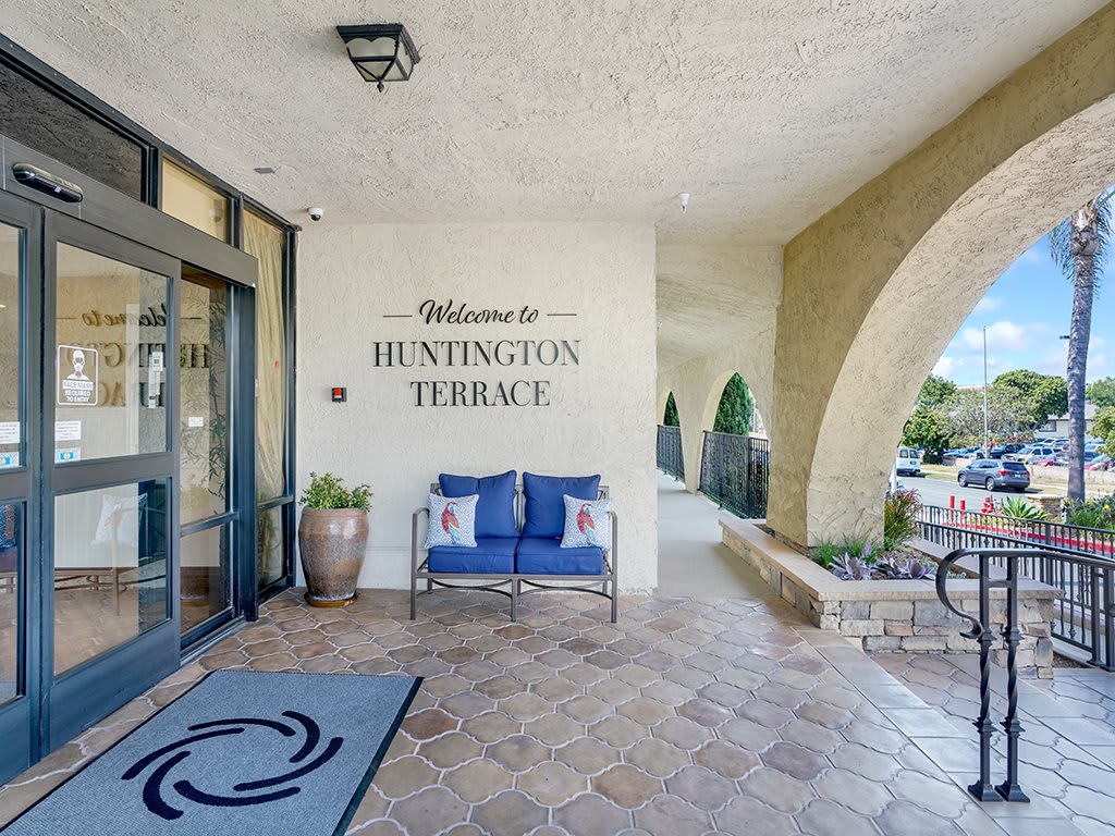 The entrance to Huntington Terrace features a welcoming sign, a comfortable bench, and decorative plants.