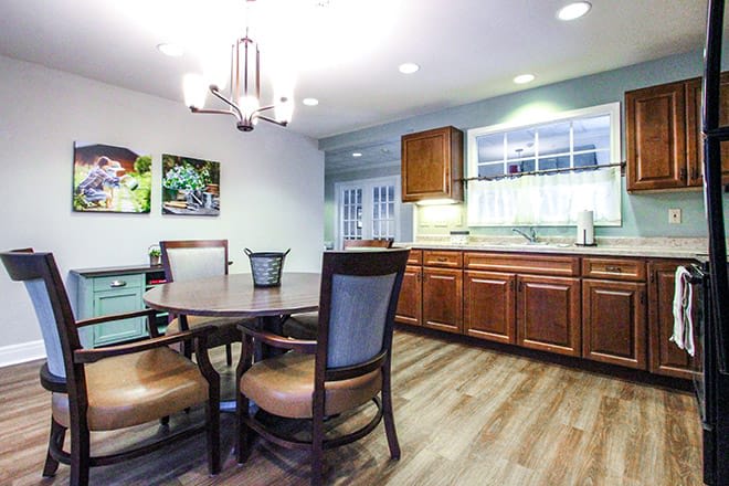 A cozy kitchen and dining area with wooden cabinets, a round dining table, and a chandelier.