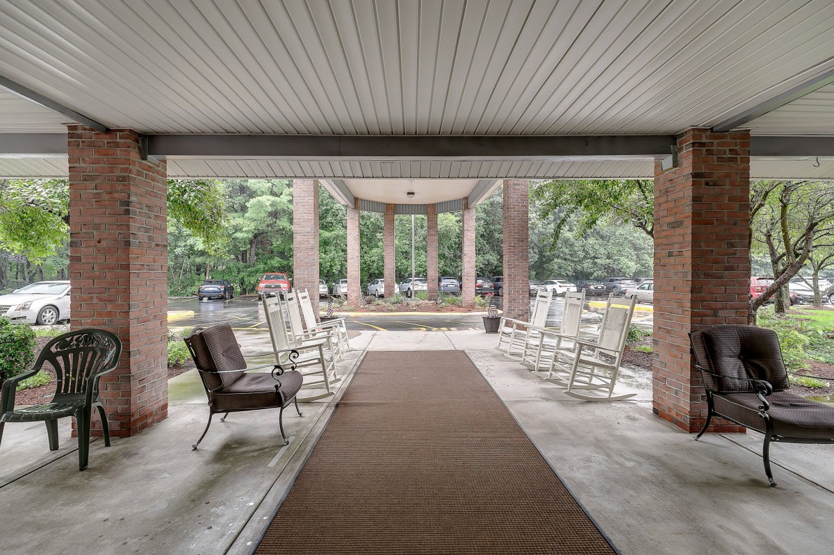 A serene covered patio area with rocking chairs and a garden view.