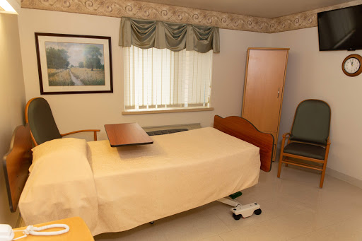 A well-furnished hospital room featuring a patient bed, a side table, and natural light coming through the window.