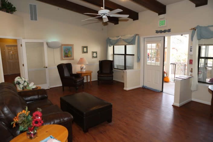 A cozy living room with wooden flooring, a ceiling fan, and comfortable seating.