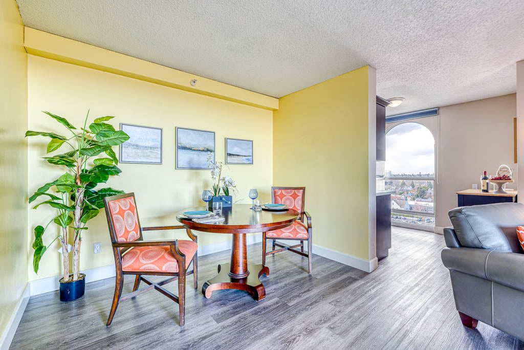 A cozy dining area with a round table and two chairs, accented by a yellow wall and decorative plants.
