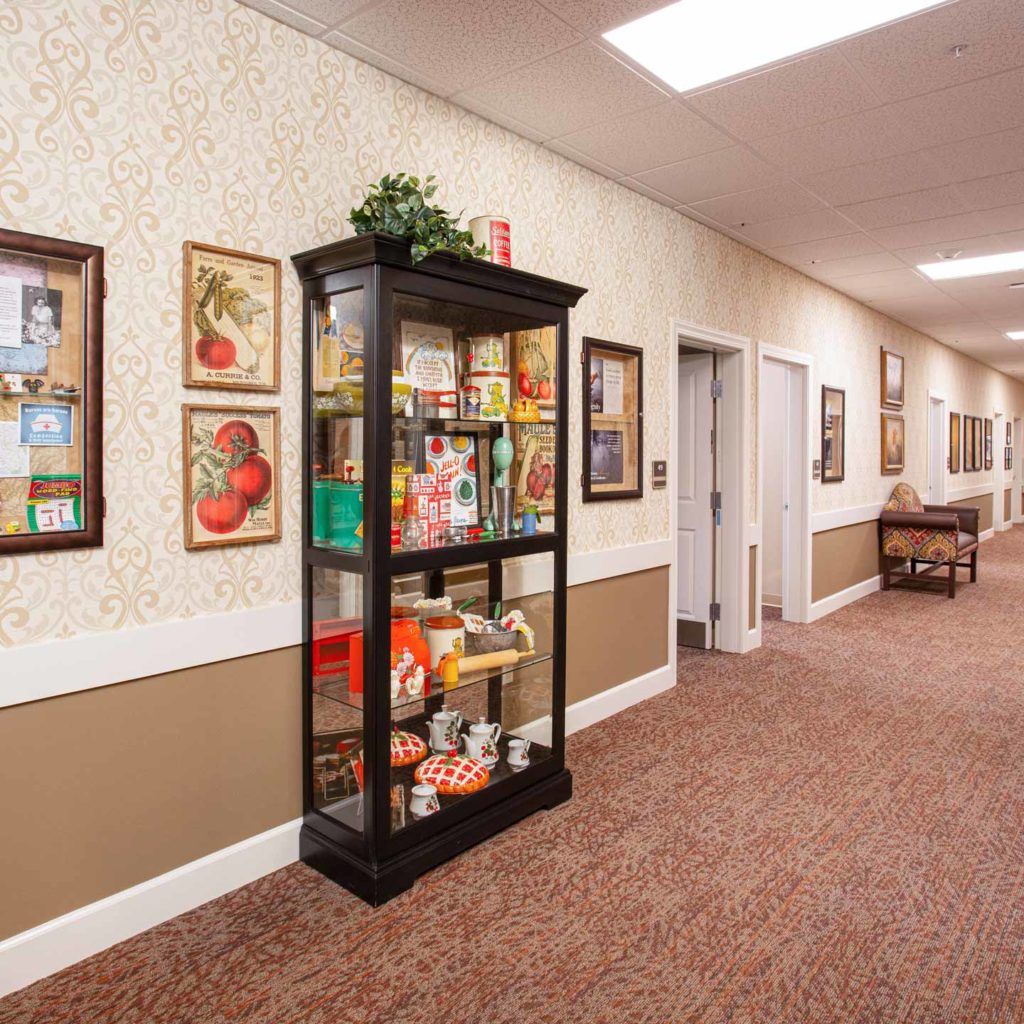 A well-decorated hallway featuring a display case filled with various items and artwork adorning the walls.