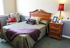 A cozy bedroom with a bed, nightstand, and upholstered chair.