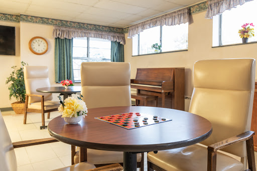 A cozy lounge area featuring a checkers table, comfortable seating, and a piano in the background.