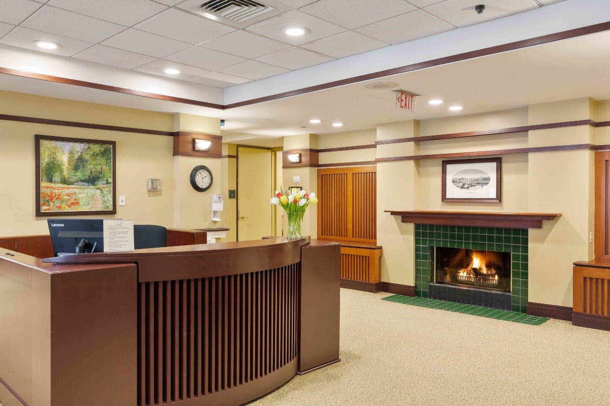 A welcoming reception area featuring a wooden desk, cozy fireplace, and comfortable decor.