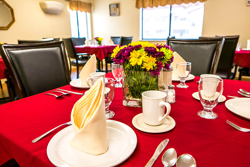 A beautifully set dining table with flowers and elegant tableware in a restaurant setting.