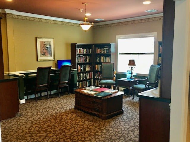 A cozy library room with bookshelves, a computer desk, and comfortable seating.