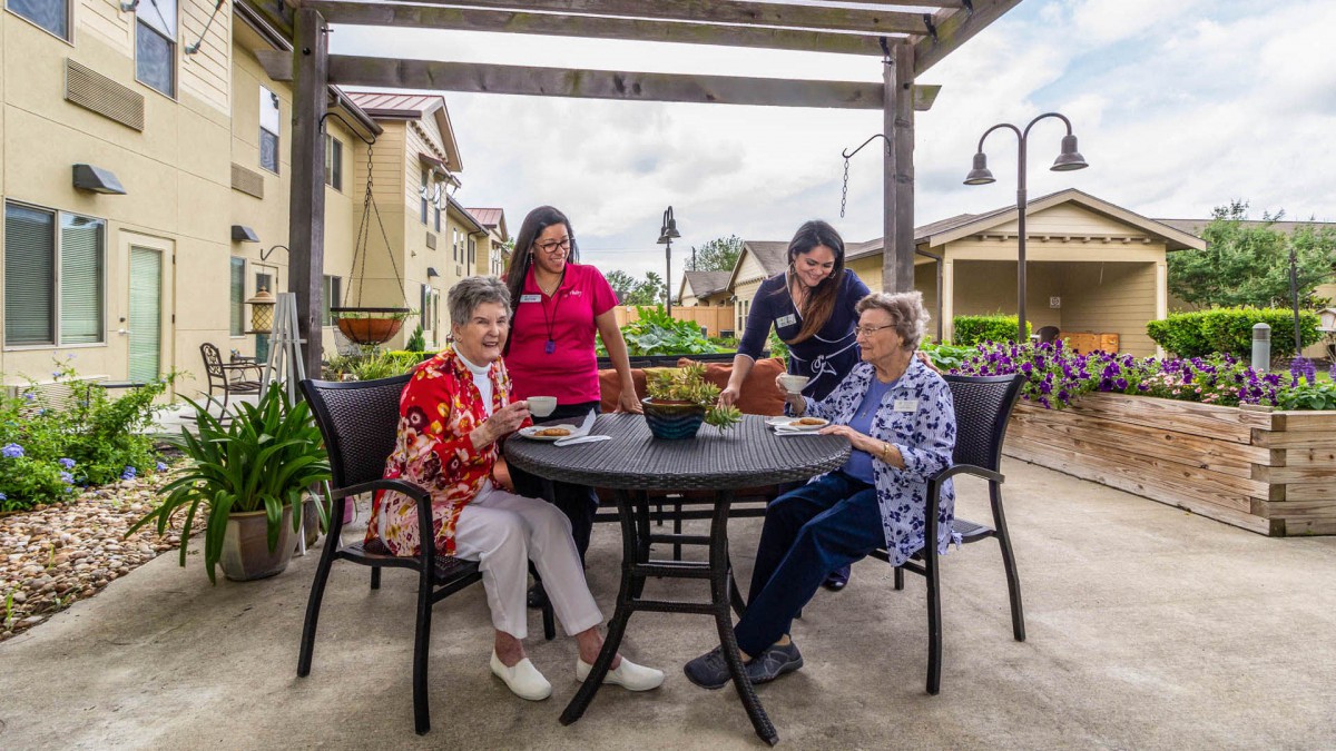 A group of people sitting around a table outdoors, enjoying each other's company.