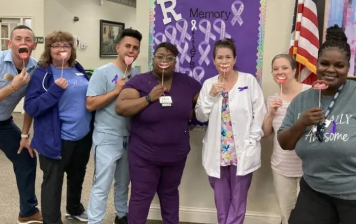 Healthcare workers pose together with purple ribbons in support of awareness.