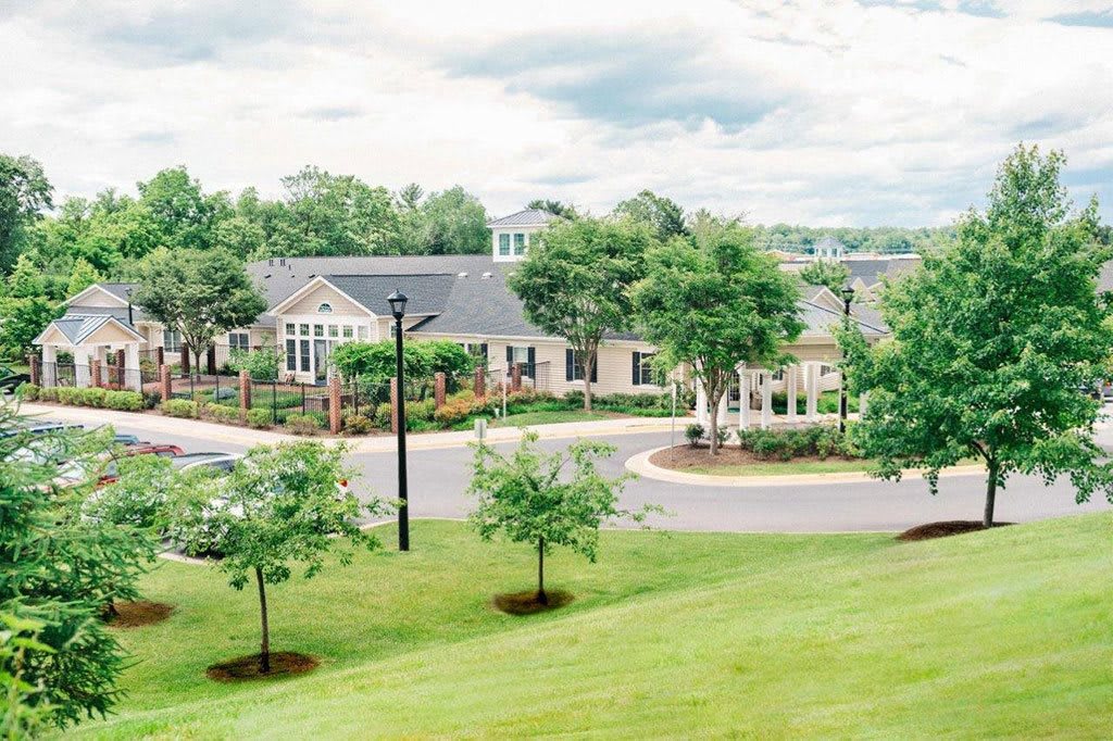 A peaceful residential neighborhood with houses and well-maintained lawns surrounded by trees.