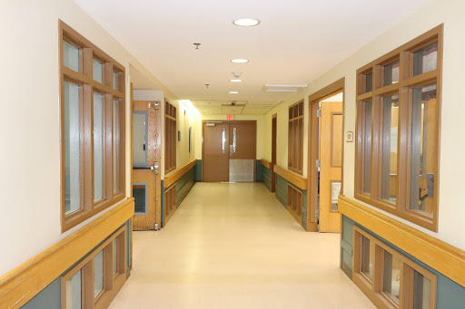 A quiet corridor within a hospital, featuring wooden accents and doors.