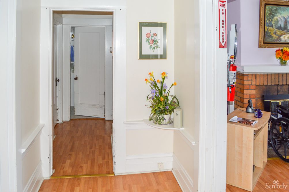 A hallway with wooden flooring, featuring a floral arrangement and artwork on the wall.