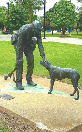 A bronze sculpture depicting a human interacting affectionately with a dog.
