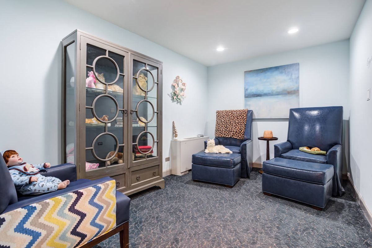 A cozy lounge area with blue armchairs and a decorative cabinet.