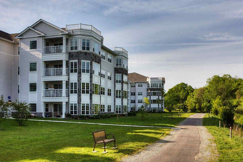 A modern apartment building with a well-kept lawn and a clear sky.
