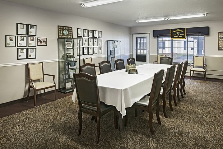 A well-arranged conference room featuring a long meeting table with chairs, carpeted floor, and decorative elements.