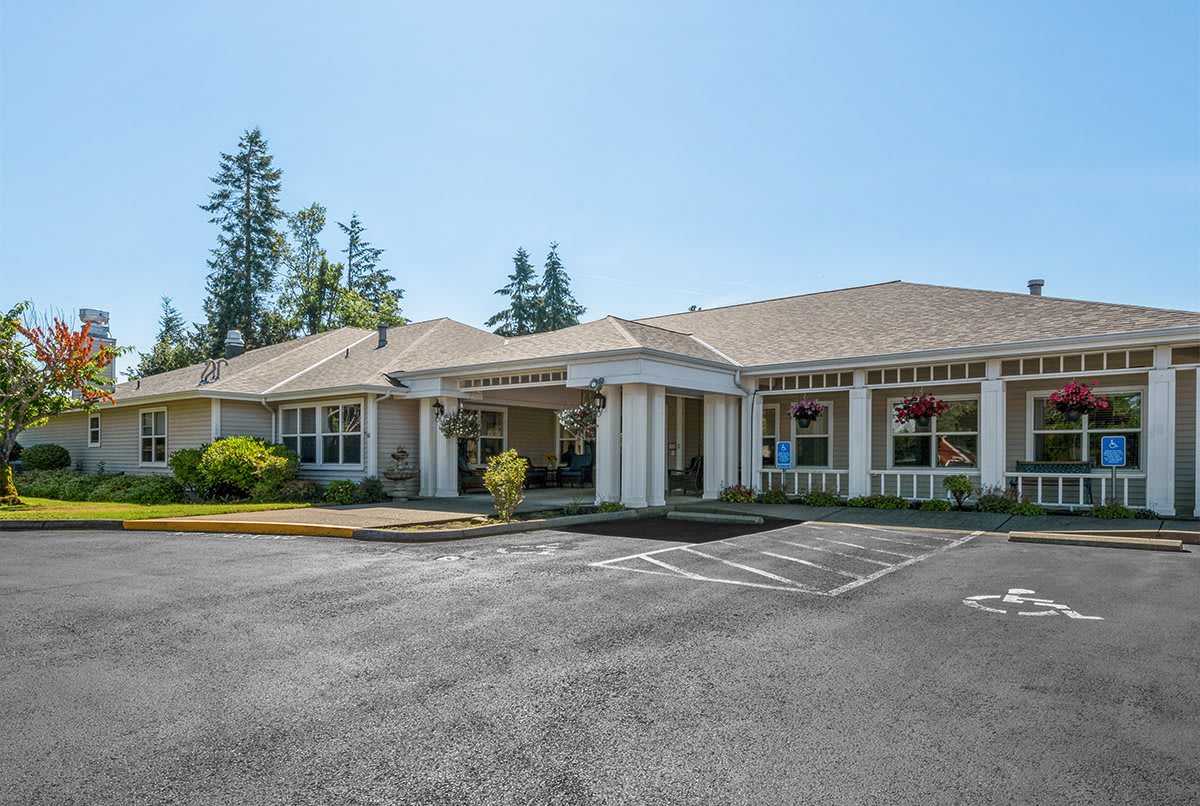 A one-story building with a spacious parking lot and clear blue sky.