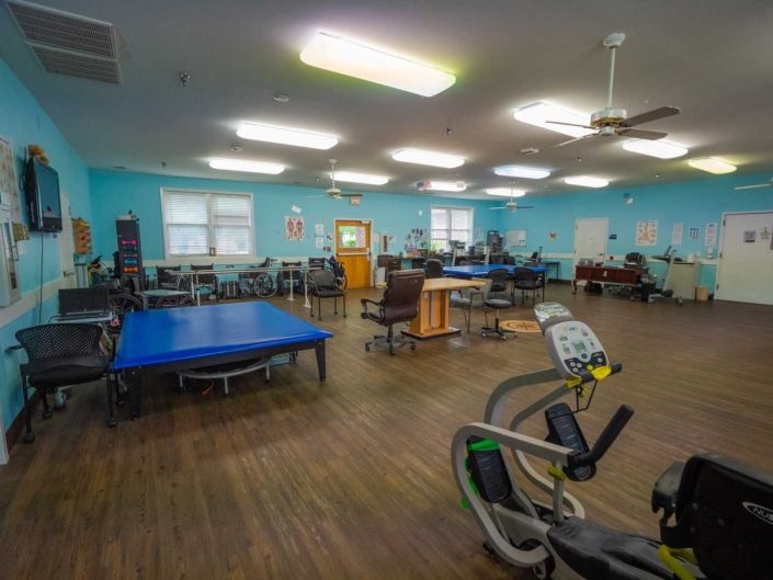A spacious rehab center with various exercise equipment and therapy stations.